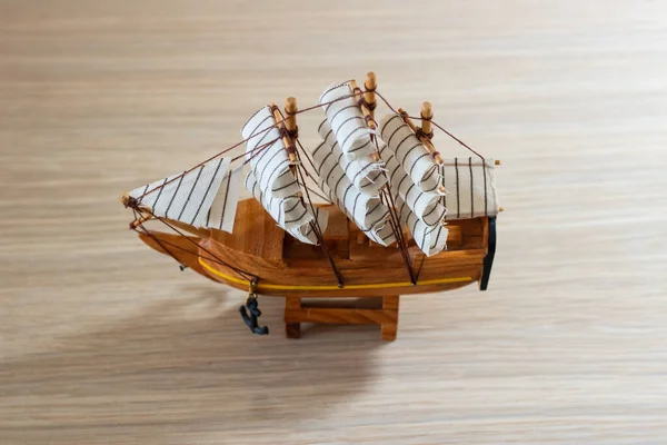 Isolated close-up of a souvenir wooden ship on a light wooden background