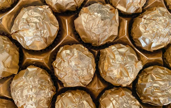 Background of candy in a gold wrapper close-up. Candy texture