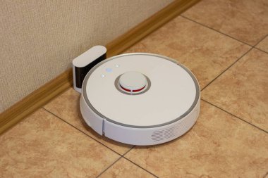 Odanın temizliği bittikten sonra robot elektrik süpürgesi şarj bölümünde. Ev yönetimi için modern elektronik teknolojiler