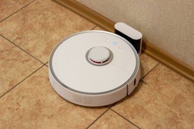 Odanın temizliği bittikten sonra robot elektrik süpürgesi şarj bölümünde. Ev yönetimi için modern elektronik teknolojiler