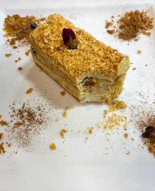 Napolyon pastasından bir parça beyaz bir tabakta duruyor.