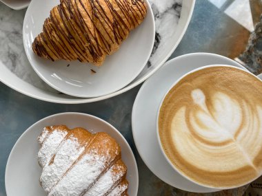 İki lezzetli kruvasan ve masanın üzerinde canlandırıcı bir kapuçino.