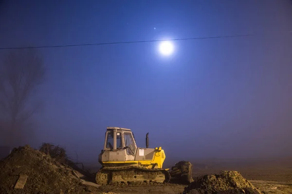 Blue excavator digger working at night on the stree