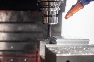 Metal çalışan CNC soğutuculu değirmen makinesi. Adam başı bir parça alüminyum. Cnc makinesinde endüstriyel metalcilik kesme işlemi.