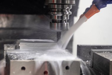 Metal çalışan CNC soğutuculu değirmen makinesi. Adam başı bir parça alüminyum. Cnc makinesinde endüstriyel metalcilik kesme işlemi.