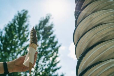 Dondurma tatlandırılmış donmuş yiyecekler genellikle atıştırmalık ya da tatlı olarak yenir. Kadın, güneşin arka planında dondurma tutuyor.