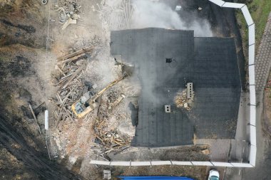 Sarı kazıcı binayı yok ediyor. Ağır iş makineleri bir tuğla binayı yıkıyor. Binanın yıkılması. Yıkım inşaat işi hava aracı fotoğraf görüntüsü