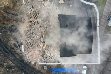 Sarı kazıcı binayı yok ediyor. Ağır iş makineleri bir tuğla binayı yıkıyor. Binanın yıkılması. Yıkım inşaat işi hava aracı fotoğraf görüntüsü