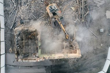 Sarı kazıcı binayı yok ediyor. Ağır iş makineleri bir tuğla binayı yıkıyor. Binanın yıkılması. Yıkım inşaat işi hava aracı fotoğraf görüntüsü