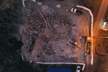 Sarı kazıcı binayı yok ediyor. Ağır iş makineleri bir tuğla binayı yıkıyor. Binanın yıkılması. Yıkım inşaat işi hava aracı fotoğraf görüntüsü