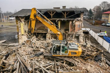Sarı kazıcı binayı yok ediyor. Ağır iş makineleri bir tuğla binayı yıkıyor. Binanın yıkılması. Yıkım inşaat işi hava aracı fotoğraf görüntüsü