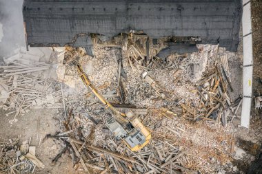 Sarı kazıcı binayı yok ediyor. Ağır iş makineleri bir tuğla binayı yıkıyor. Binanın yıkılması. Yıkım inşaat işi hava aracı fotoğraf görüntüsü