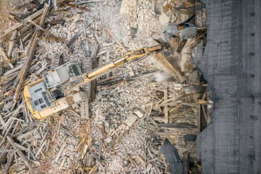 Sarı kazıcı binayı yok ediyor. Ağır iş makineleri bir tuğla binayı yıkıyor. Binanın yıkılması. Yıkım inşaat işi hava aracı fotoğraf görüntüsü