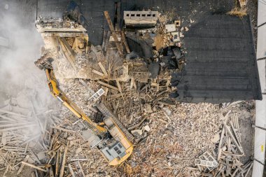 Sarı kazıcı binayı yok ediyor. Ağır iş makineleri bir tuğla binayı yıkıyor. Binanın yıkılması. Yıkım inşaat işi hava aracı fotoğraf görüntüsü