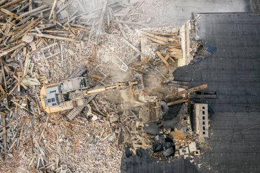 Sarı kazıcı binayı yok ediyor. Ağır iş makineleri bir tuğla binayı yıkıyor. Binanın yıkılması. Yıkım inşaat işi hava aracı fotoğraf görüntüsü