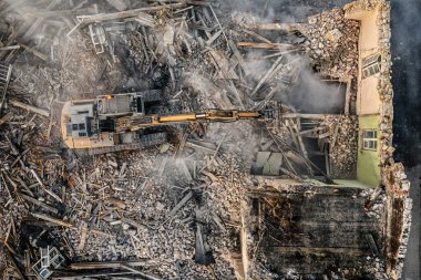 Sarı kazıcı binayı yok ediyor. Ağır iş makineleri bir tuğla binayı yıkıyor. Binanın yıkılması. Yıkım inşaat işi hava aracı fotoğraf görüntüsü
