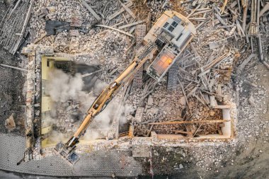 Sarı kazıcı binayı yok ediyor. Ağır iş makineleri bir tuğla binayı yıkıyor. Binanın yıkılması. Yıkım inşaat işi hava aracı fotoğraf görüntüsü