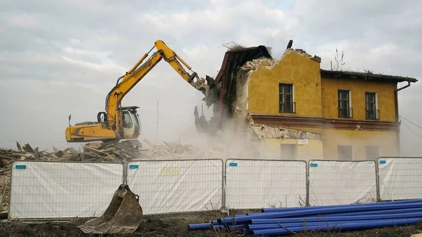 Yellow excavator destroys building. Heavy duty machine is demolishing a brick building. Demolition of the building . Demolition construction work aerial drone photo view