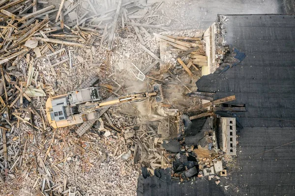 Sarı kazıcı binayı yok ediyor. Ağır iş makineleri bir tuğla binayı yıkıyor. Binanın yıkılması. Yıkım inşaat işi hava aracı fotoğraf görüntüsü