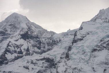 Kışın İsviçre dağlarının manzarası. Bulutlardaki Eiger, Monoch ve Jungfrau. İsviçre 'nin Jungfrauregion bölgesindeki İsviçre Alpleri