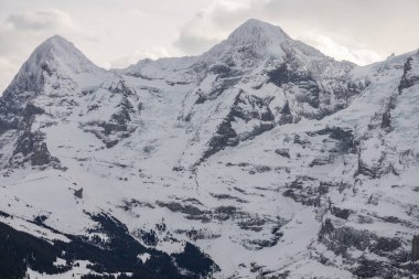 Kışın İsviçre dağlarının manzarası. Bulutlardaki Eiger, Monoch ve Jungfrau. İsviçre 'nin Jungfrauregion bölgesindeki İsviçre Alpleri