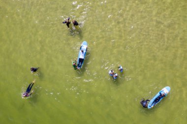 Denizde sörf yapan insanların hava aracı görüntüsü. Yaz sporu sörf yapmayı öğreniyor. Baltık Denizi 'nde sörf yapmak Jastarnia, Polonya, Avrupa