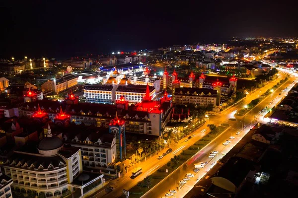 Side at night. Hotels and streets at night in Turkey. Illuminated resort at night in Antalya, Turkey  aerial drone photo view
