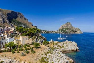 Porticello, Santa Flavia, Sicilya, İtalya 'daki Sant Elia körfezi plajı, Sicilya turkuvaz suları, kayalık uçurumlar, renkli evler ve Bagheria' daki Akdeniz kıyı şeridi manzarası..