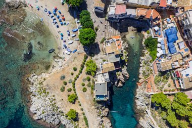 Porticello, Santa Flavia, Sicilya, İtalya 'daki Sant Elia körfezi plajı, Sicilya turkuvaz suları, kayalık uçurumlar, renkli evler ve Bagheria' daki Akdeniz kıyı şeridi manzarası..
