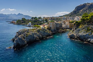 Porticello, Santa Flavia, Sicilya, İtalya 'daki Sant Elia körfezi plajı, Sicilya turkuvaz suları, kayalık uçurumlar, renkli evler ve Bagheria' daki Akdeniz kıyı şeridi manzarası..