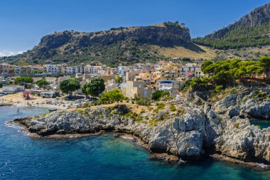 Porticello, Santa Flavia, Sicilya, İtalya 'daki Sant Elia körfezi plajı, Sicilya turkuvaz suları, kayalık uçurumlar, renkli evler ve Bagheria' daki Akdeniz kıyı şeridi manzarası..