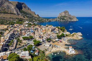 Porticello, Santa Flavia, Sicilya, İtalya 'daki Sant Elia körfezi plajı, Sicilya turkuvaz suları, kayalık uçurumlar, renkli evler ve Bagheria' daki Akdeniz kıyı şeridi manzarası..