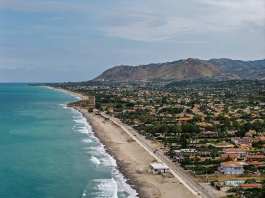 Sicilya, İtalya 'nın kuzeyinde büyüleyici bir Sicilya sahil kasabası olan Campofelice di Roccella' nın insansız hava aracı görüntüsü geleneksel tatil evleri, kıyı şeridi ve panoramik Tiren Denizi manzaralarını gösteriyor..