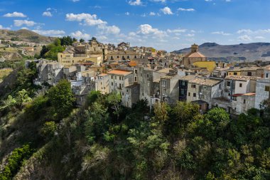 Polizzi Generosa 'nın hava aracı görüntüsü, Sicilya' nın Sicilya, İtalya 'daki Madonie Dağları' nın geleneksel taş binaları ve panoramik manzarasını gösteren kayalık uçurumlara tünemiş Sicilya dağ kasabası..