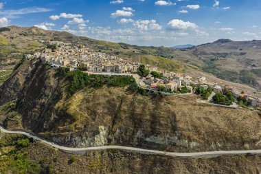 Polizzi Generosa 'nın hava aracı görüntüsü, Sicilya' nın Sicilya, İtalya 'daki Madonie Dağları' nın geleneksel taş binaları ve panoramik manzarasını gösteren kayalık uçurumlara tünemiş Sicilya dağ kasabası..