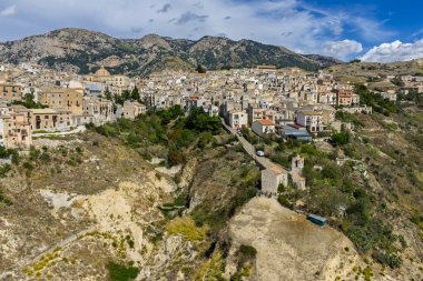 Polizzi Generosa 'nın hava aracı görüntüsü, Sicilya' nın Sicilya, İtalya 'daki Madonie Dağları' nın geleneksel taş binaları ve panoramik manzarasını gösteren kayalık uçurumlara tünemiş Sicilya dağ kasabası..
