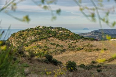 Mountainous central Sicilian landscape near Campofelice di Roccella, Italy, featuring rolling hills, distant Tyrrhenian Sea views, and the volcanic Islands on the horizon under.