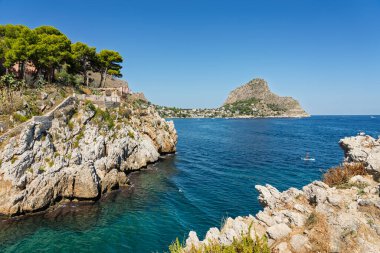 Sant Elia bay beach in Porticello town, Santa Flavia, Sicily, Italy. Sicilian turquoise waters, rocky cliffs, colorful houses, and Mediterranean coastline panorama in Bagheria.