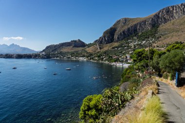 Sant Elia bay beach in Porticello town, Santa Flavia, Sicily, Italy. Sicilian turquoise waters, rocky cliffs, colorful houses, and Mediterranean coastline panorama in Bagheria.