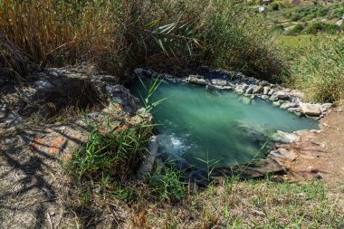 Sulfur springs in Sclafani Bagni,  Sicilian mountain town in the Madonie Mountains, featuring natural geothermal pools, steam rising from the water, and surrounding scenic landscapes, Sicily, Italy.