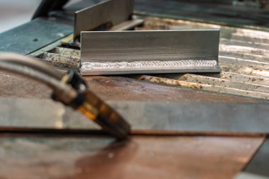 Robot çeliği kaynak yapar. Kaynak kafa. Kaynak robotu. CNC kaynaklama. Kaynak işleminin robotlaştırılması ve otomasyonu. Robot kaynak çeliği. Endüstriyel kaynak robotu ve metal parçalarıyla çalışıyor.