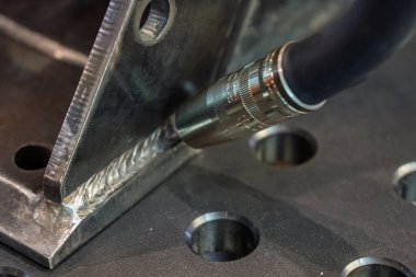 Robot çeliği kaynak yapar. Kaynak kafa. Kaynak robotu. CNC kaynaklama. Kaynak işleminin robotlaştırılması ve otomasyonu. Robot kaynak çeliği. Endüstriyel kaynak robotu ve metal parçalarıyla çalışıyor.