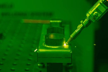 Metal, parlak uçan kıvılcımlar üzerinde lazer kaynaklama yapan bir insan elinin yakın çekimi. Kaynak işleminin robotlaştırılması ve otomasyonu. Robot kaynak çeliği. Endüstriyel kaynak ve metal parçalarıyla çalışma.