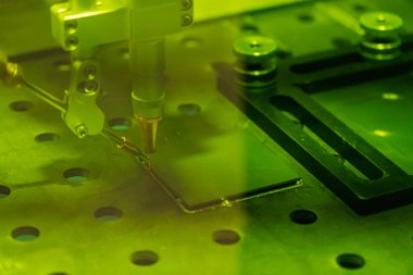 Metal, parlak uçan kıvılcımlar üzerinde lazer kaynaklama yapan bir insan elinin yakın çekimi. Kaynak işleminin robotlaştırılması ve otomasyonu. Robot kaynak çeliği. Endüstriyel kaynak ve metal parçalarıyla çalışma.