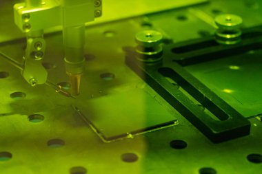 Metal, parlak uçan kıvılcımlar üzerinde lazer kaynaklama yapan bir insan elinin yakın çekimi. Kaynak işleminin robotlaştırılması ve otomasyonu. Robot kaynak çeliği. Endüstriyel kaynak ve metal parçalarıyla çalışma.