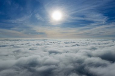 Güneşli bir günde, yoğun sis ve bulutların üzerine buhar yayan endüstriyel bacaların hava aracı görüntüsü, enerji santrali ve fabrika manzarası. Güneşli bir günde bulutların üzerindeki panorama. Bulut fabrikası.