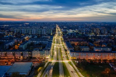 Aydınlatılmış sokaklar ve insansız hava araçlarından görünen binalar, kentsel altyapının ve spor alanının parlayan ışıkları günbatımında ve alacakaranlıkta modern metropol atmosferi yaratıyor..