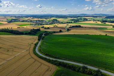 Polonya 'da Opole ve Nysa yakınlarındaki kırsal köylerin ve tarım alanlarının insansız hava aracı görüntüsü geometrik tarım arazileri, dağınık evler, dolambaçlı kır yolları ve gün ışığında yeşil çayırlar gösteriyor..
