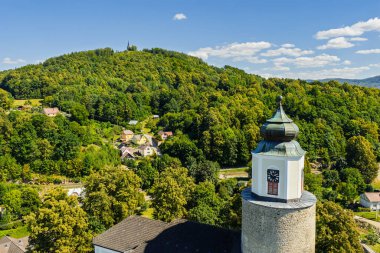 Çek Cumhuriyeti 'nin Bozi Hora tepesindeki tarihi kilisesinin, geleneksel çatılarının, yeşilliğin çevresindeki Zulova kasabasının insansız hava aracı görüntüsü ve gün ışığında yakalanan huzurlu kasaba düzeni..
