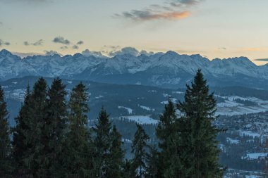 Zakopane yakınlarındaki Czarna Gora 'dan gelen Tatra Dağları' nın insansız hava aracı görüntüsü, kış sıradağlarını, ormanlı tepeleri, köy manzarasını ve sakin akşamüstü alp manzarasını gösteriyor..